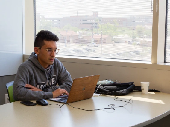 student sitting at study room table with laptop